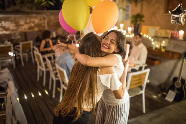 Woman welcoming guest on her birthday dinner party and recieving gifts